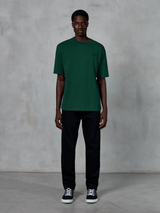 Alpinestars Essentials Ageless SS Tee, Short Sleeve T-Shirt, Pine Green, featuring a subtle black chest logo, worn by a model with black pants and sneakers, casual lifestyle streetwear with a relaxed fit