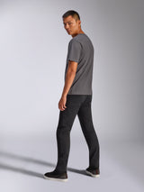 Male model wearing Alpinestars Shaded CSF Tee, Short Sleeve T-Shirt, Charcoal Gray, back view showing the graphic, paired with black pants and sneakers, casual motorsport-inspired streetwear
