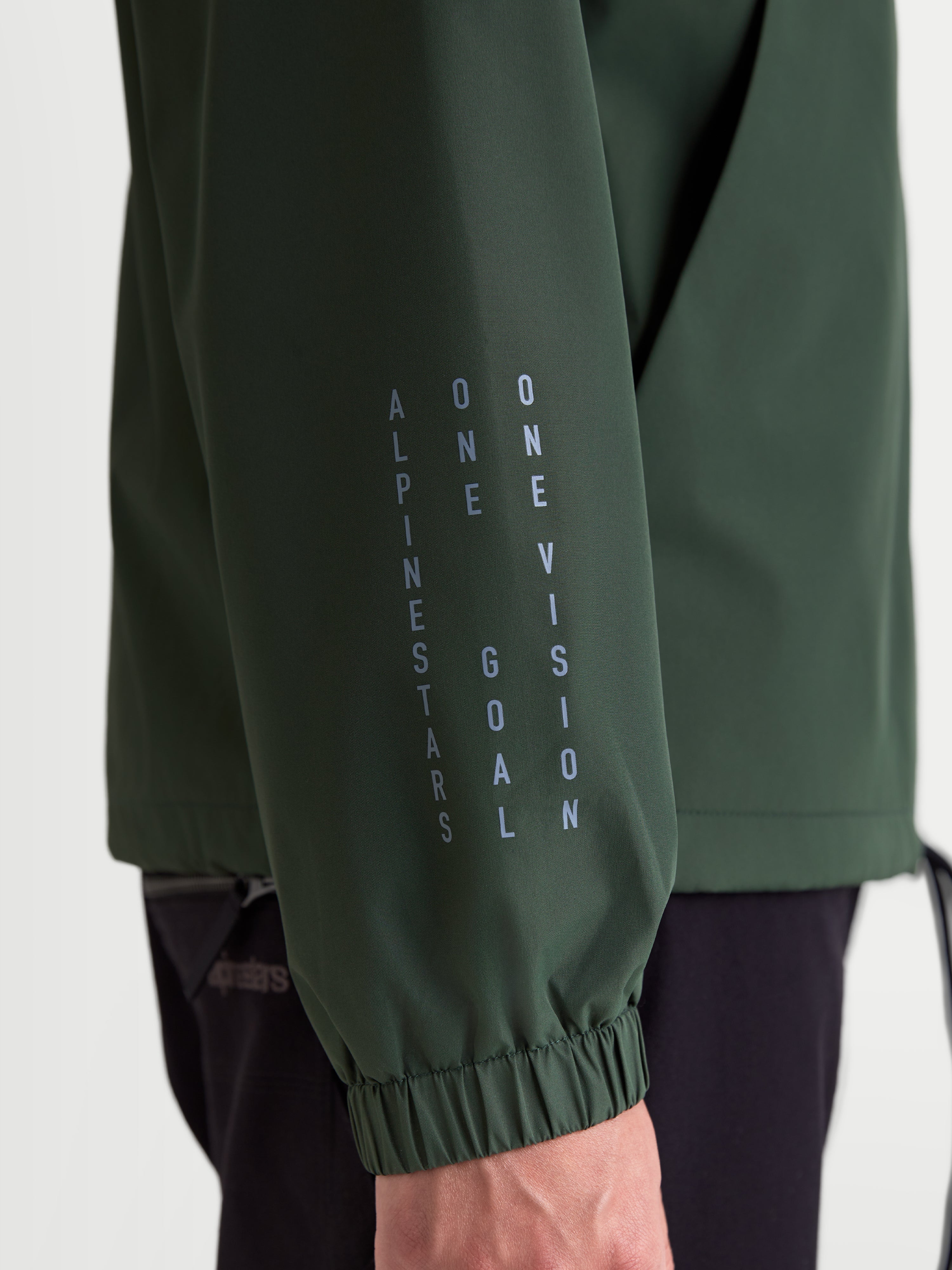 Alpinestars Speeder Resolve Windbreaker Jacket, Lightweight Sportswear in Pine Green, close-up of sleeve with elastic cuff and vertical Alpinestars One Goal One Vision branding.