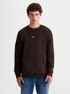 Alpinestars Guise Oversized Crew, Sportswear Fleece Pullover for everyday lifestyle, Unisex relaxed fit shown on model, Brown, Cotton and Recycled Polyester, featuring a kangaroo pocket and embroidered Alpinestars logo branding on chest and sleeve for a premium motorsport-inspired look.