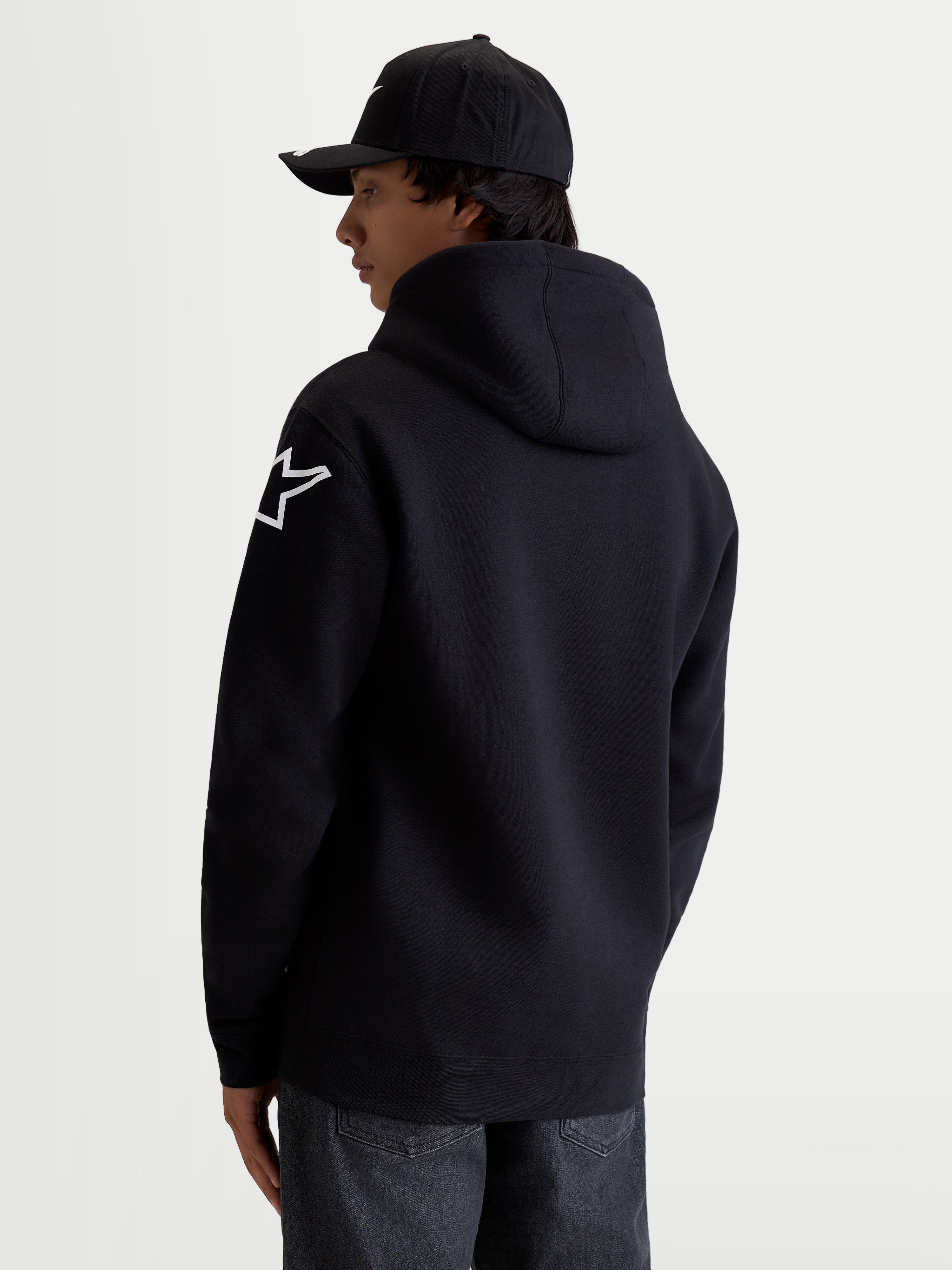 Alpinestars Velocifier Hoodie, Men's Pullover Fleece in Black, Cotton and Recycled Polyester blend, featuring a white Astars shoulder logo, self-lined hood, and ribbed cuffs. Casual off-bike sportswear for motorsport enthusiasts, back view on model.