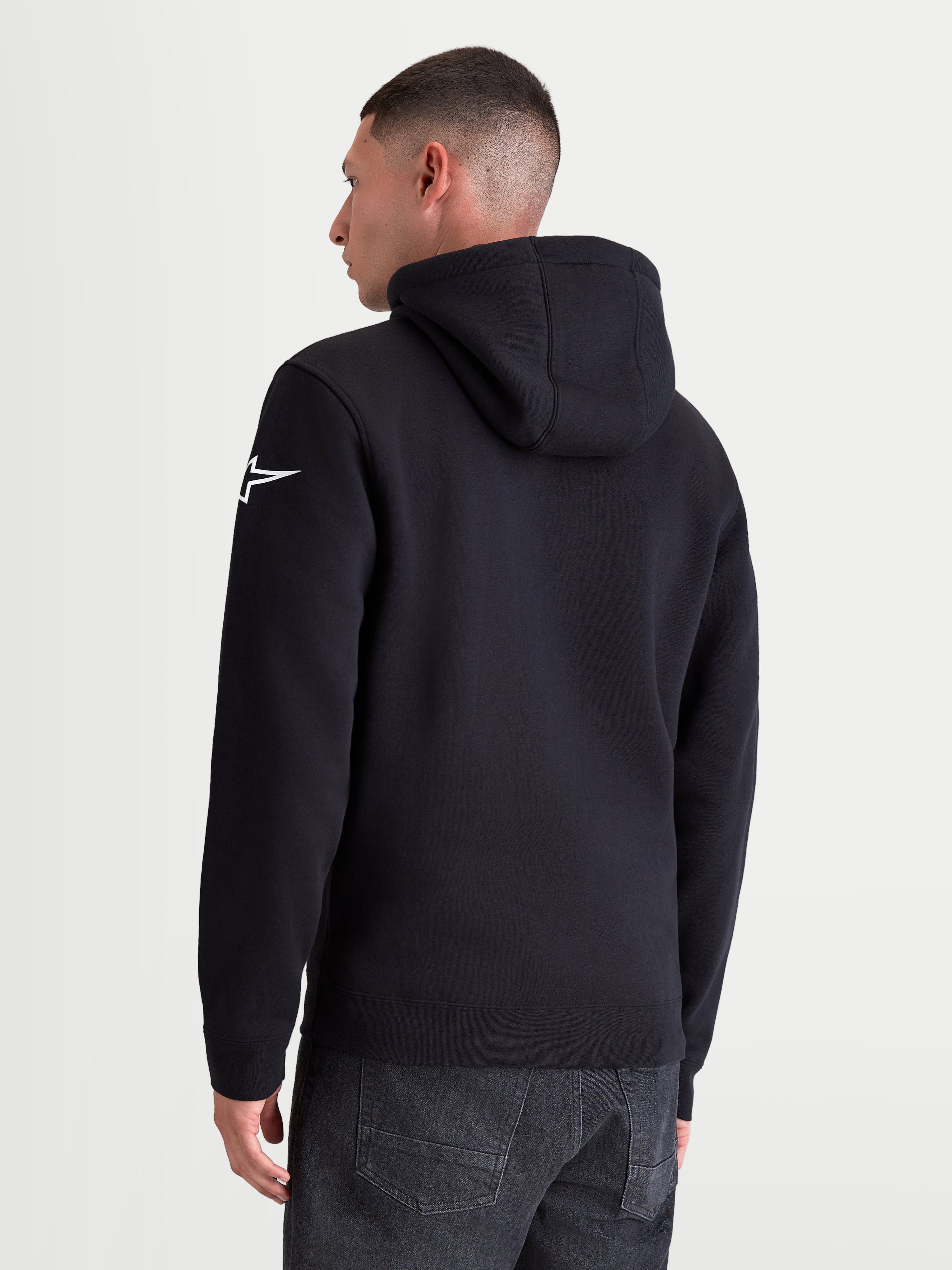 Alpinestars Race Wordmark Hoodie, Casual Sportswear Pullover Fleece, Rear View on Model, Black and White, featuring the white Ageless star logo on the left sleeve, self-lined hood, and ribbed cuffs. Constructed from a premium cotton and recycled polyester blend for everyday comfort.