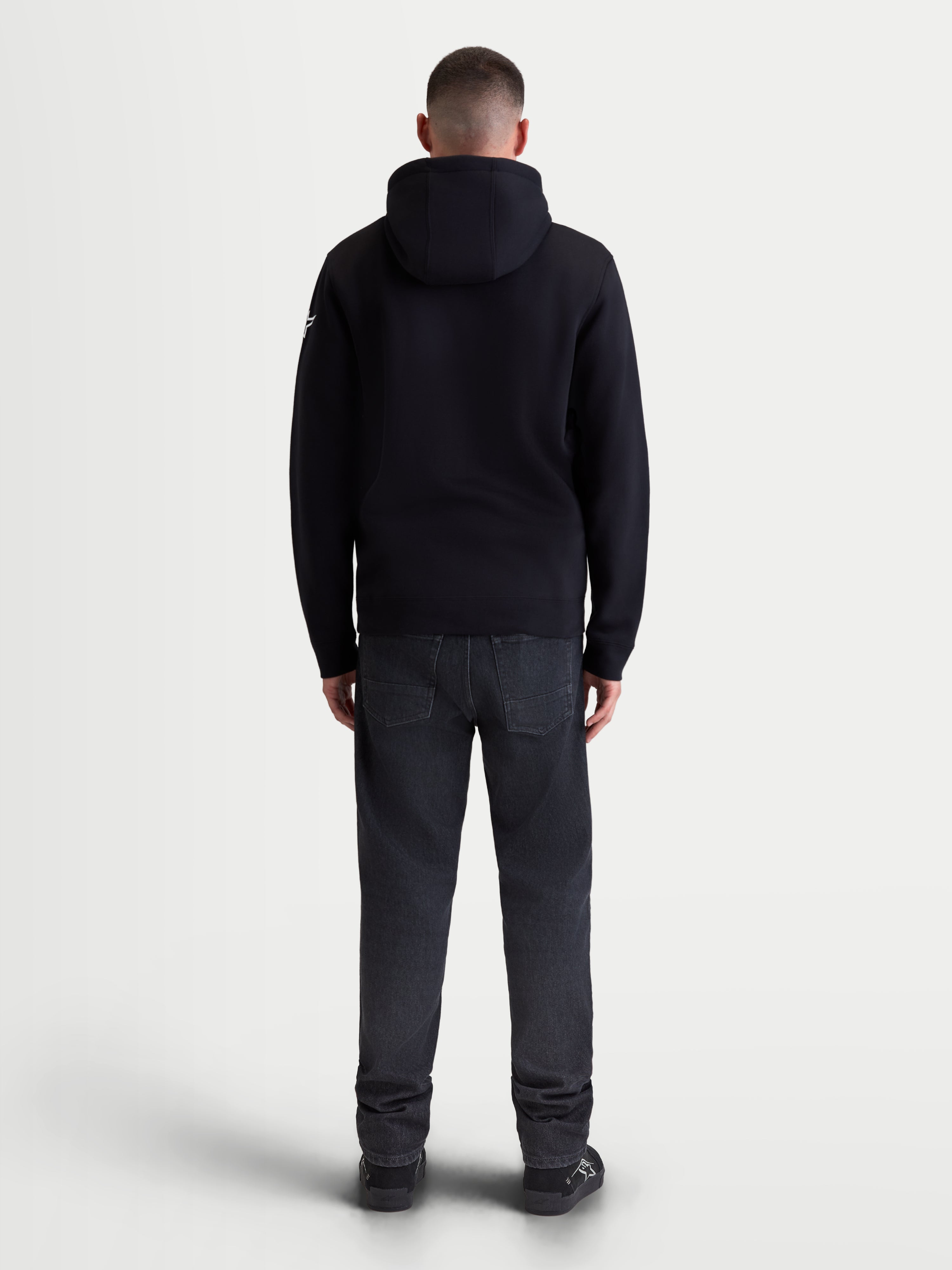 Alpinestars Race Wordmark Hoodie, Men's Sportswear Pullover Fleece, Black and White, Rear view of model wearing the black hooded sweatshirt, featuring a self-lined hood and comfortable cotton-blend construction for daily motorsport-inspired lifestyle wear.