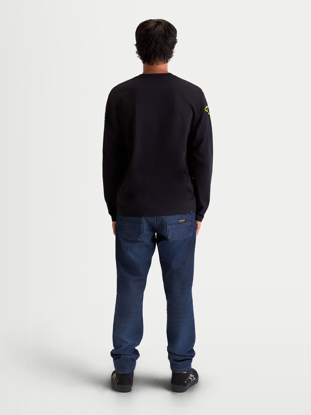 Alpinestars Velocifier CSF Tee, Long Sleeve Sportswear T-Shirt, Back View on Model, Black with Yellow Shoulder Logos, Motorsport-Inspired Casual Wear, Cotton and Recycled Polyester Blend, Ribbed Cuffs