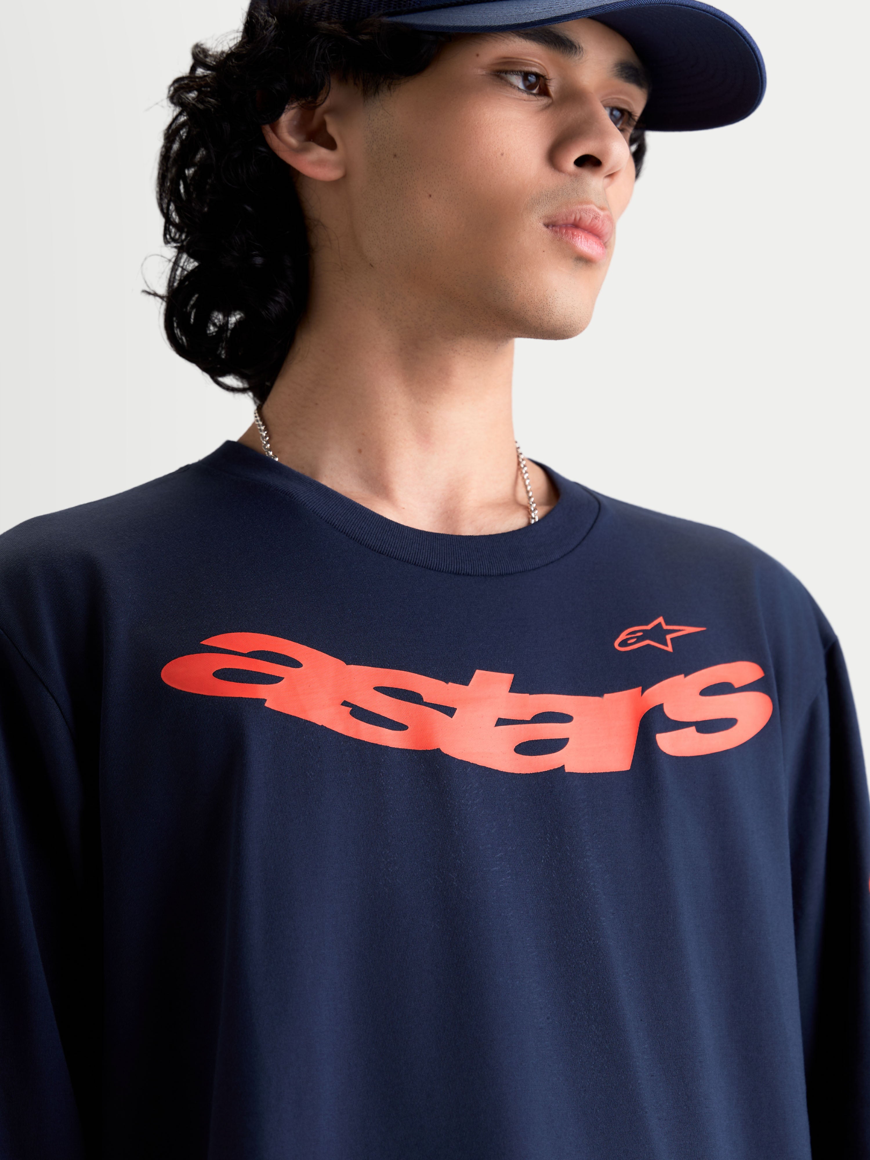 Alpinestars Velocifier CSF Tee - Long Sleeve, Motorsport-inspired casual sportswear on-model, Navy Blue with curved Orange Astars chest graphic, soft cotton blend.