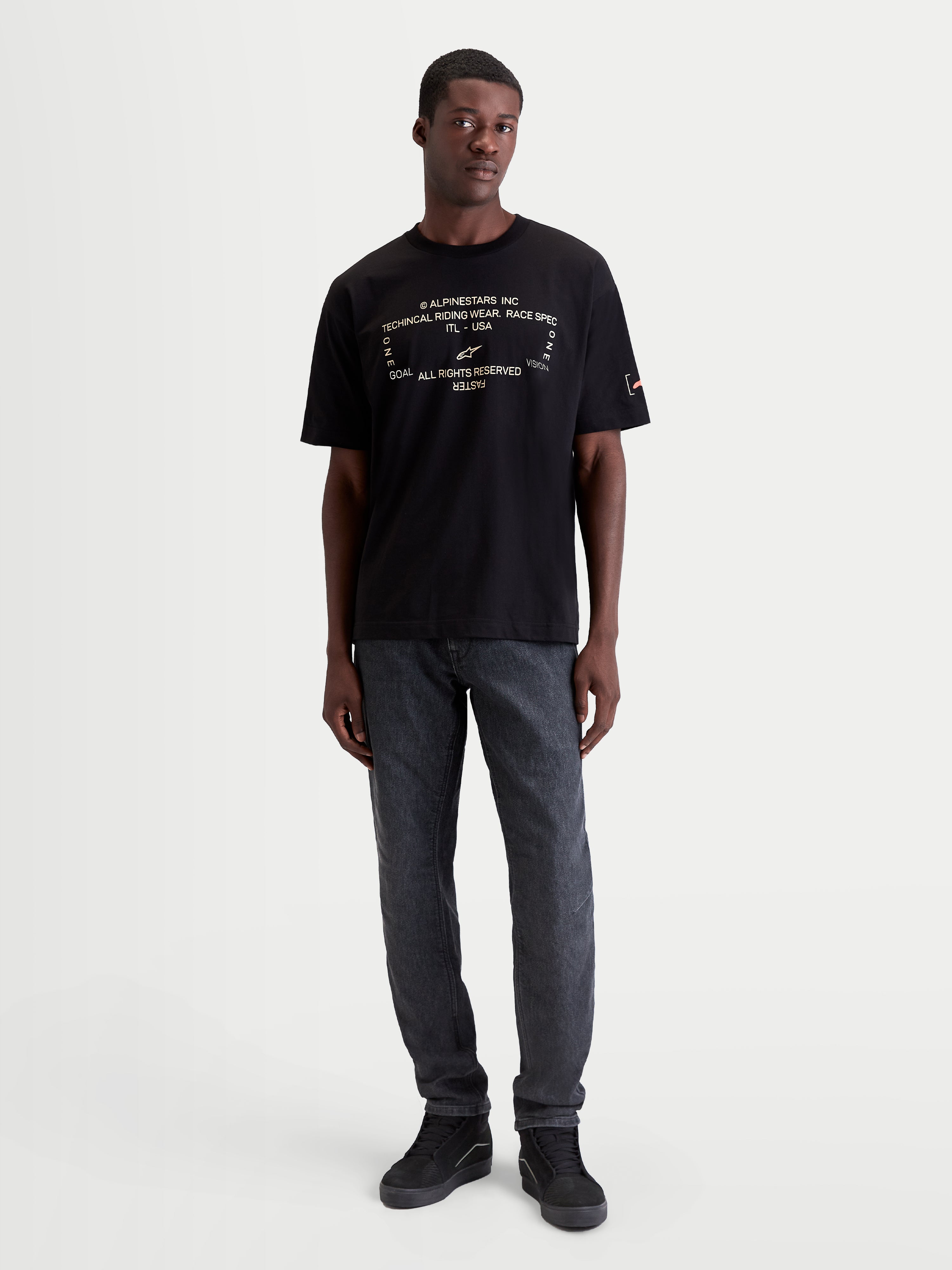 Alpinestars Infinity Oversized CSF Tee, Men's Short Sleeve Sportswear T-shirt in Black. This oversized casual tee features a technical white front graphic and a relaxed fit, crafted from a soft cotton-poly blend for everyday off-bike comfort and motorsport lifestyle style. Shown on a model.