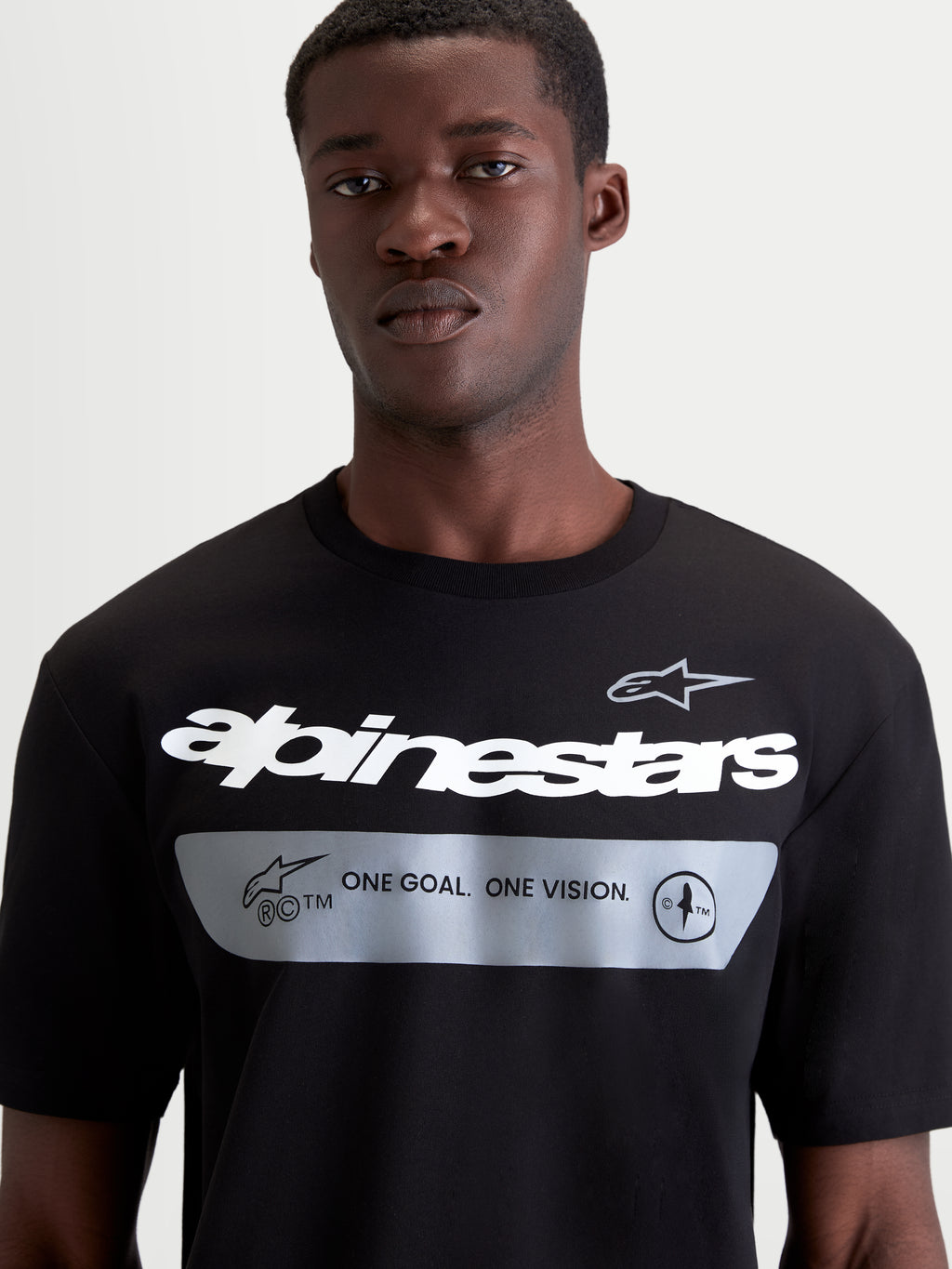 Alpinestars Singular CSF Tee, Short Sleeve Casual Sportswear T-shirt, Black with white Alpinestars word graphic and "ONE GOAL. ONE VISION." brand manifesto, premium combed ring-spun cotton blend, on-model front close-up view showing chest graphic detail.