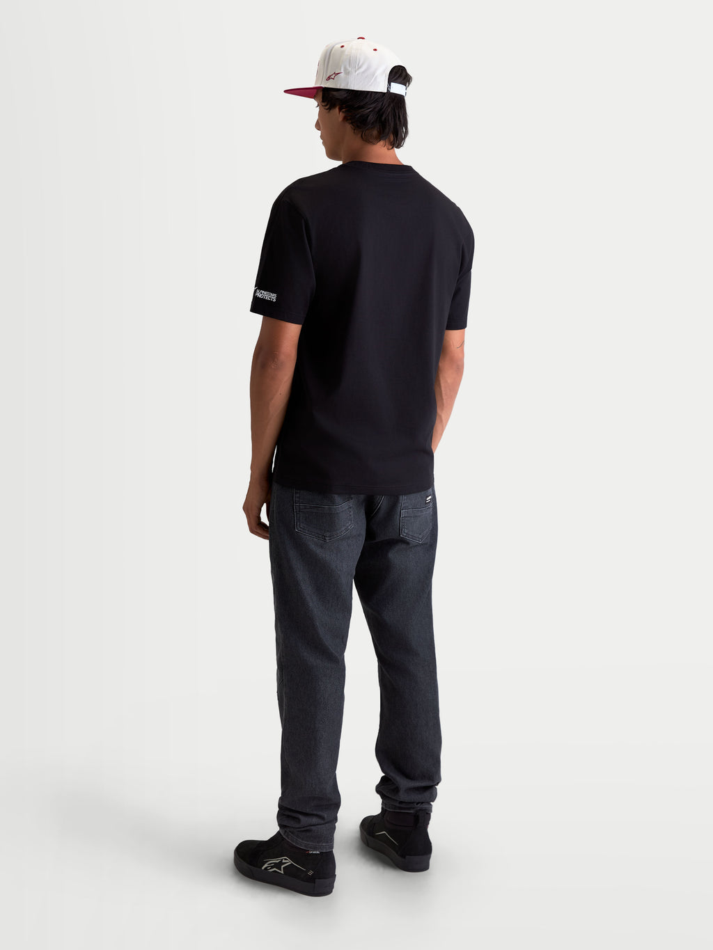 Alpinestars P1 CSF Tee, Men's and Women's Short Sleeve Sportswear T-Shirt, Black, rear view on model showing 'Alpinestars Protects' sleeve branding, soft 60/40 cotton-poly blend for everyday motorsport style.