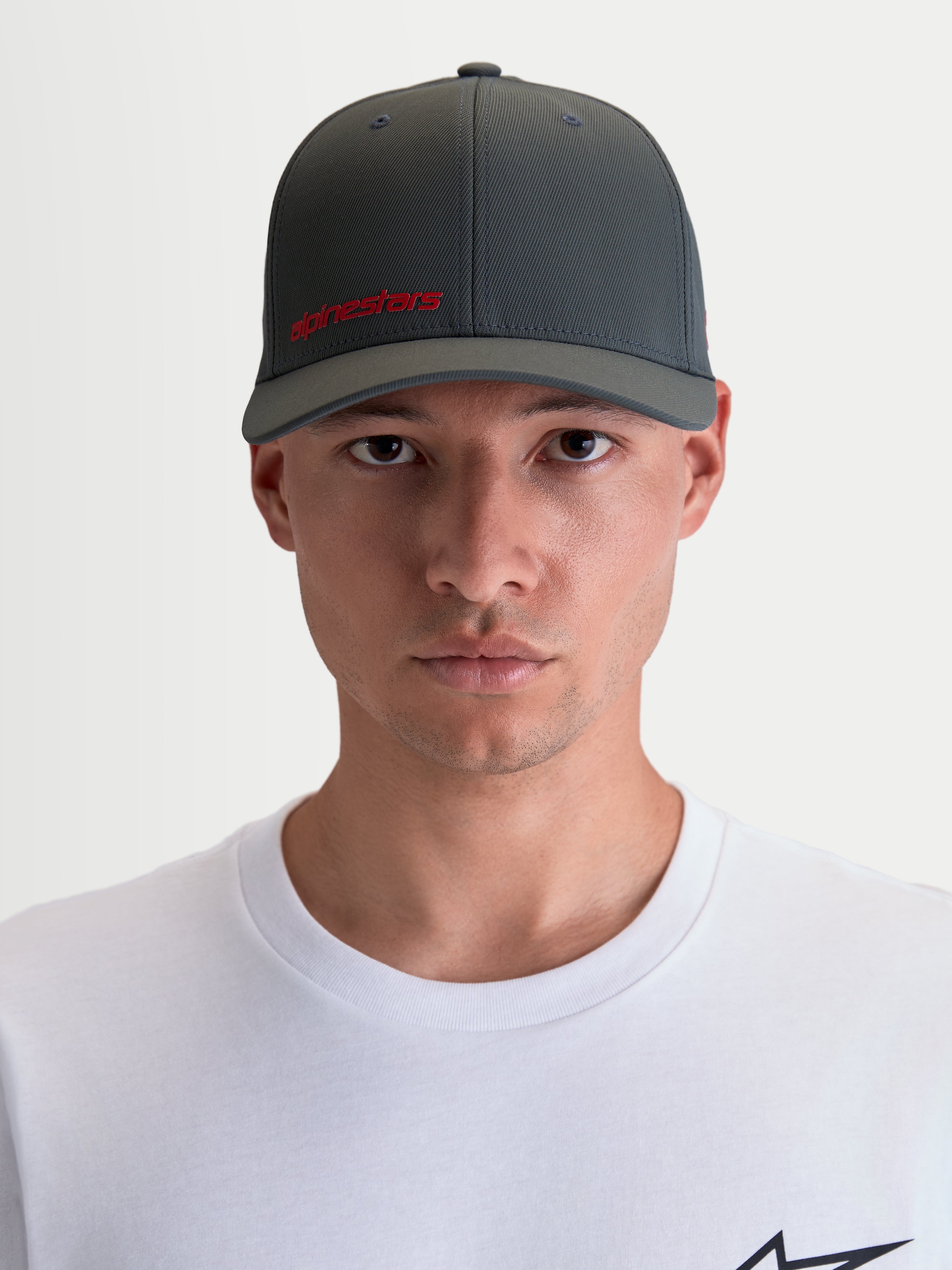 Alpinestars Points Hat, Sportswear Curved Bill Cap for Men and Women, On-Model Front View, Dark Grey with Red Alpinestars Logo, Lightweight Nylon Tactel Fabric with Flex-back Fit.