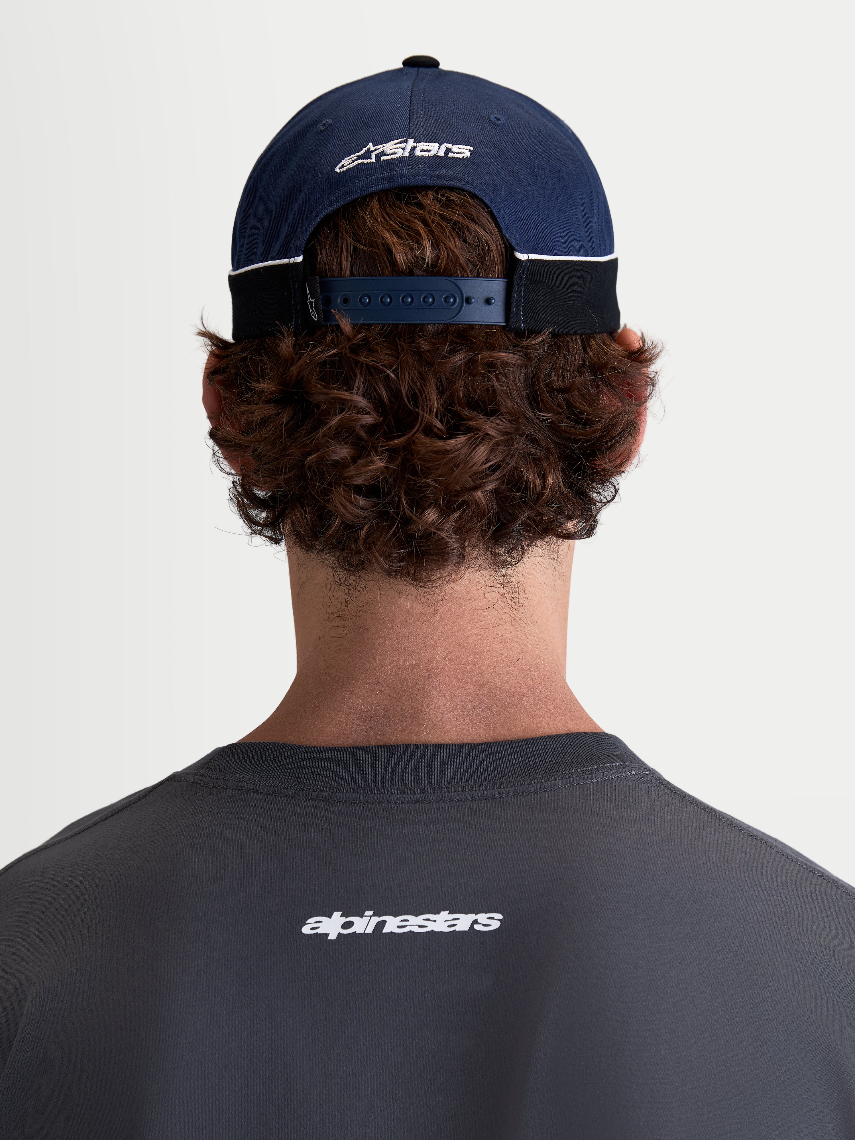 Alpinestars 500 Snapback Hat, Motorsport-inspired Sportswear Baseball Cap, Navy Blue and Black, 100% Cotton Twill construction with an adjustable snapback closure and embroidered Astars logo, rear view on model.