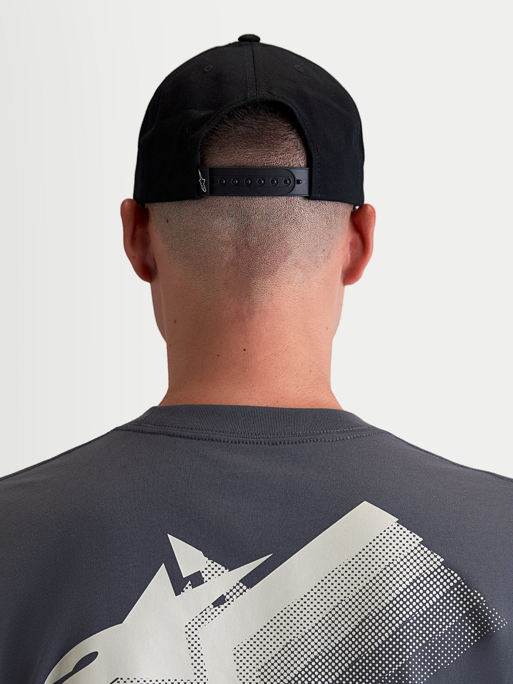 Alpinestars Combo Logo Snapback Hat, Sportswear Cap for Men and Women, Black, Durable Cotton Twill, Rear View on Model showing the Adjustable Snapback Closure and Small White Logo Detail.