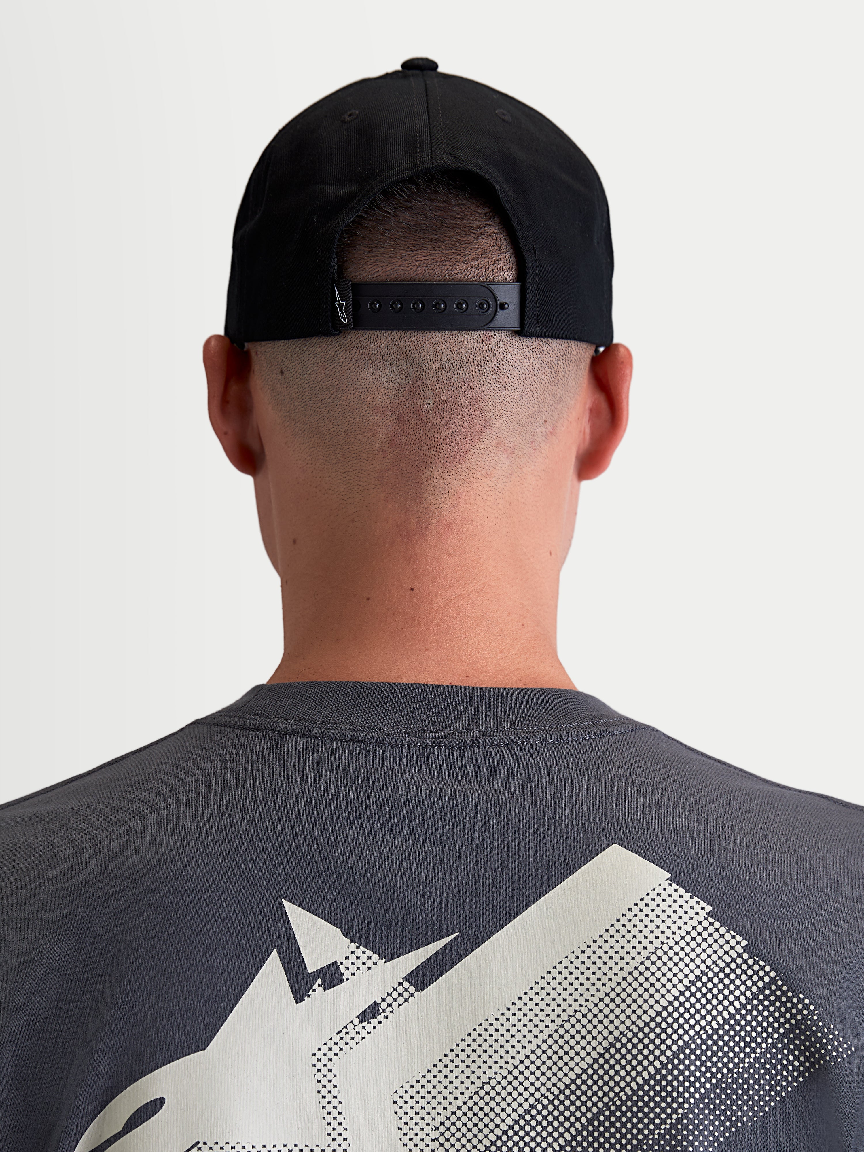 Alpinestars Combo Logo Snapback Hat, Sportswear Cap for Men and Women, Black, Durable Cotton Twill, Rear View on Model showing the Adjustable Snapback Closure and Small White Logo Detail.