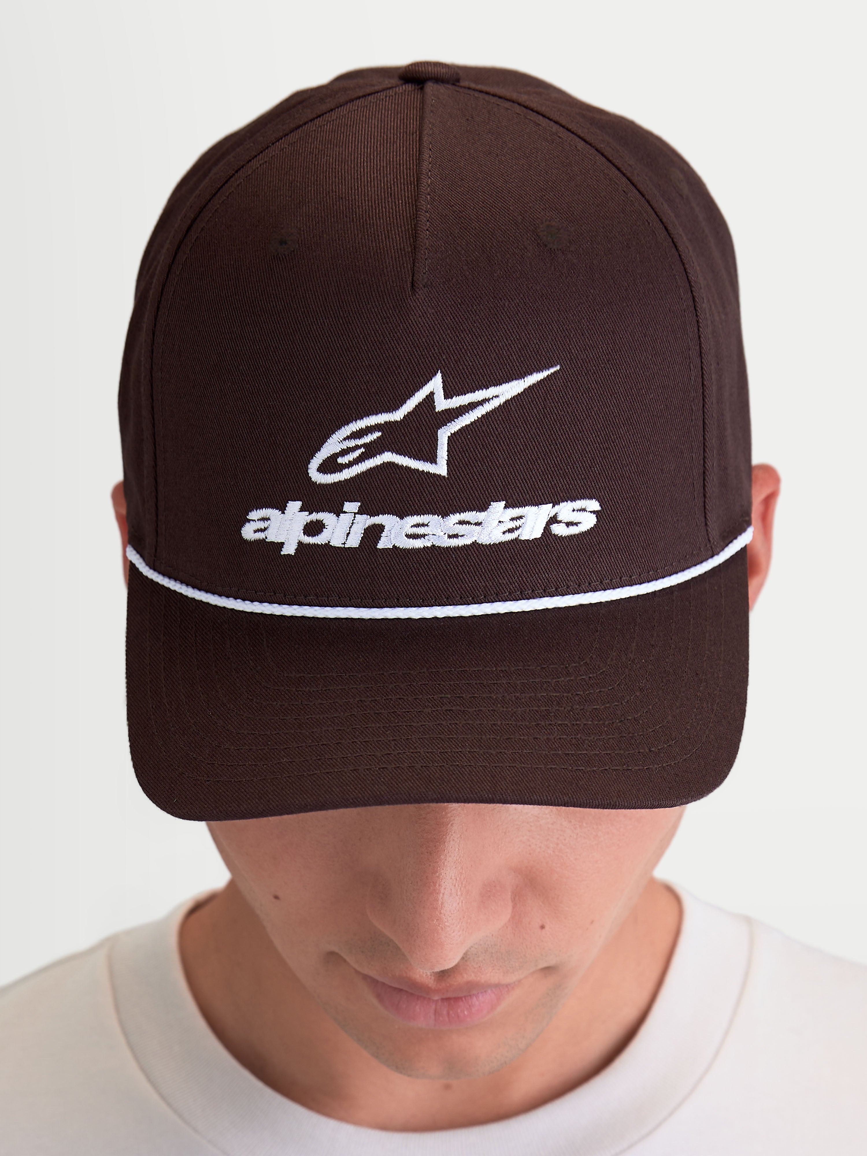 Alpinestars Combo Logo Snapback Hat, Casual Sportswear Cap, Brown with White Embroidery, featuring front Astars logo and wordmark, curved bill, and structured crown, premium cotton twill construction, shown on model.