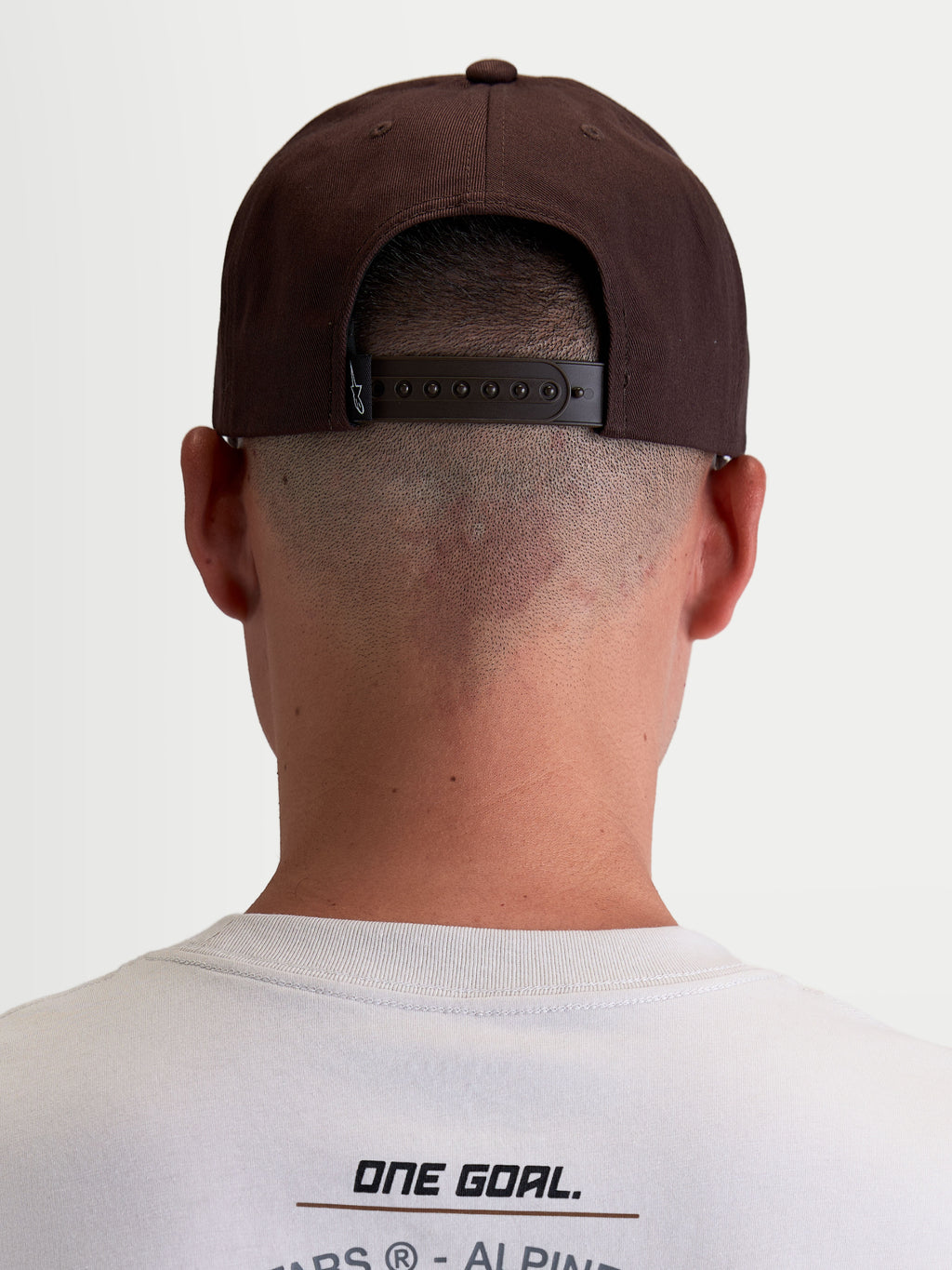 Alpinestars Combo Logo Snapback Hat, Casual Motorsport Sportswear Cap for Men and Women, Brown, Durable Twill Construction, Rear View on Model showing Adjustable Snapback Closure and Branded Label.