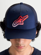 Alpinestars Meteorite Trucker Hat, Sportswear Mesh Cap for Men and Women, Navy Blue with Red and White Astars gravel texture logo patch, featuring a structured crown and curved bill, on-model front view.