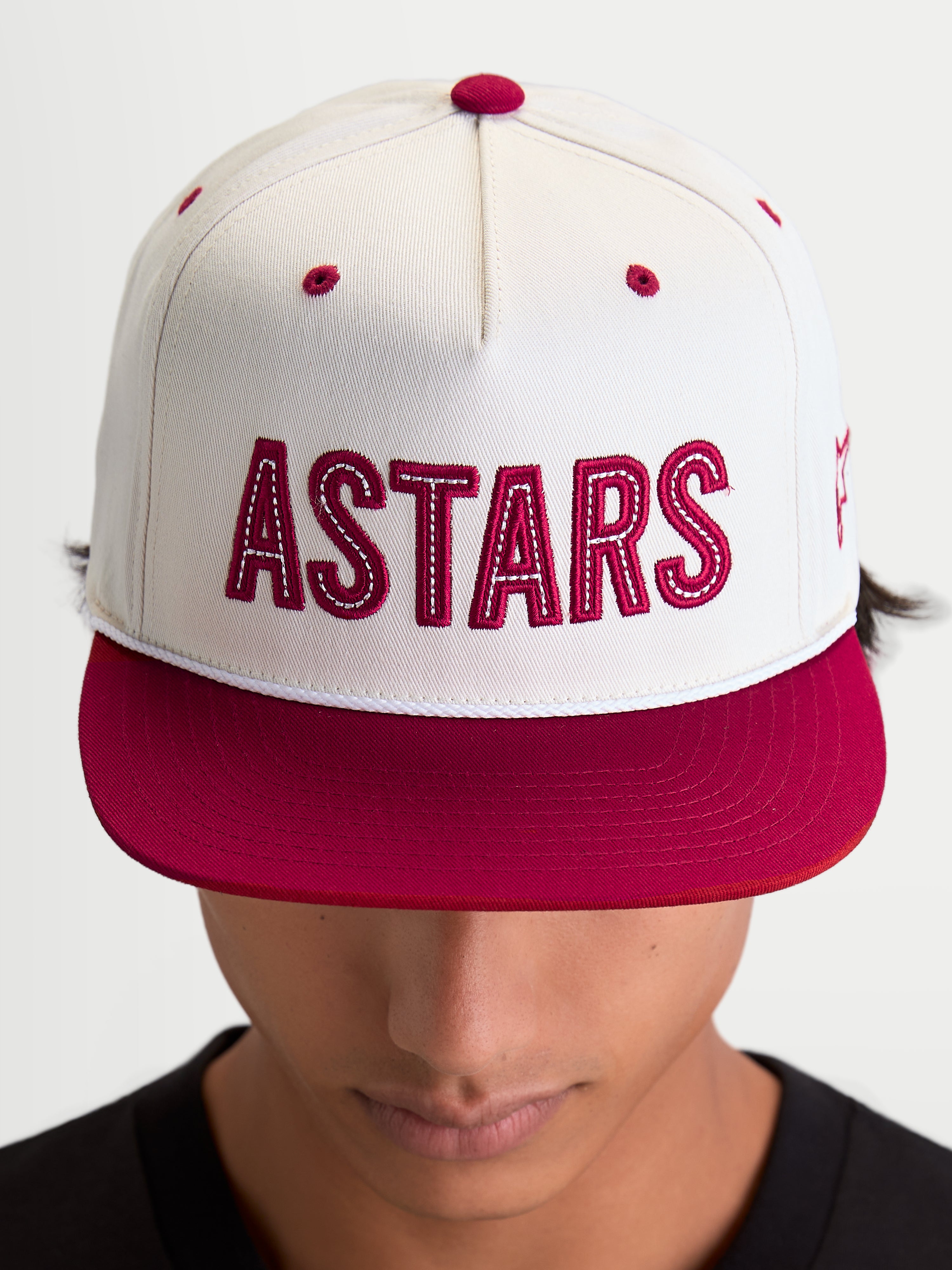 Alpinestars Stadium Snapback Hat, Sportswear Flat Bill Cap, Off White and Red, featuring a bold front 'ASTARS' logo applique with contrast stitching and a structured crown, shown on model.
