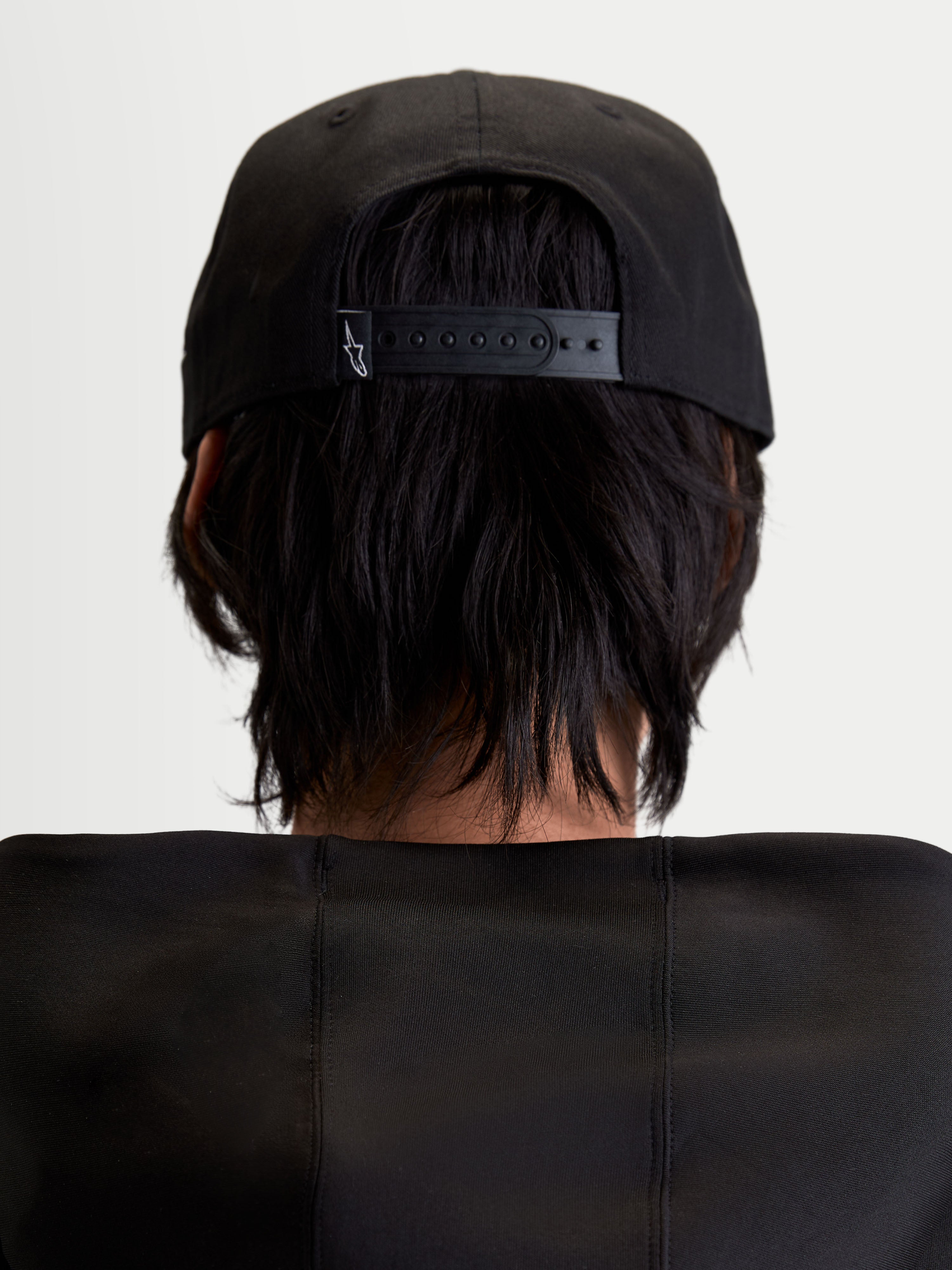 Alpinestars Label Snapback Hat, Black Sportswear Cap for Men and Women, Rear View on Model showing the Adjustable Snapback Closure with small white logo, structured cotton twill construction.