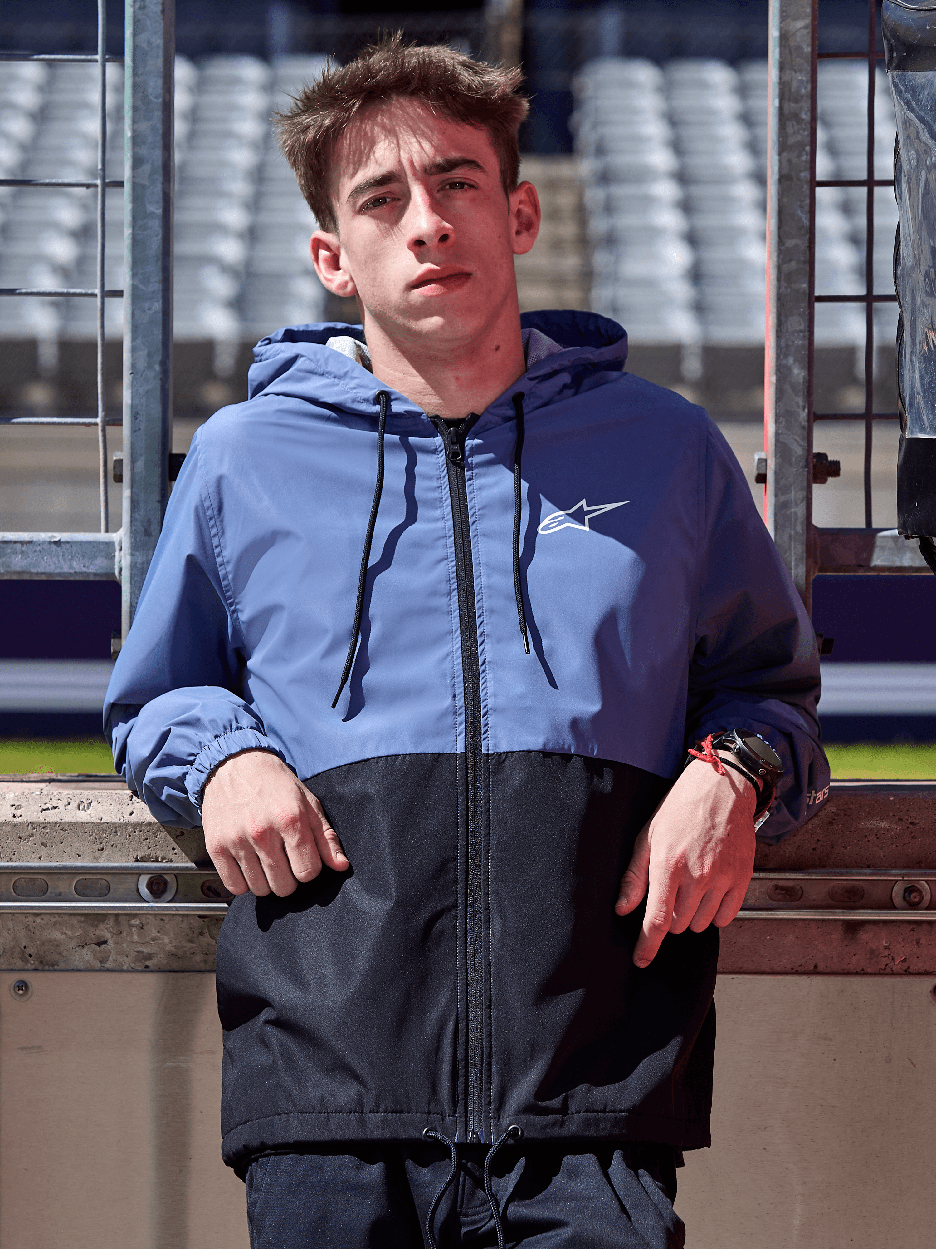 Alpinestars Speeder Windbreaker Jacket, Slate Blue and Black, hooded windbreaker with blocked body design, white logo on chest, casual lifestyle apparel worn at a racetrack