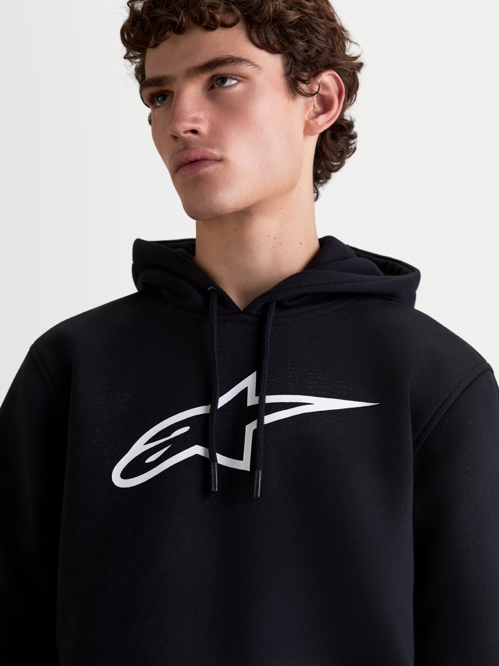 Alpinestars Ageless V3 Hoodie, Men's Sportswear Pullover Fleece, Black and White, close-up on-model view featuring a large white chest logo and drawstring hood.