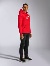 Alpinestars Ageless V3 Hoodie, Red with White Embroidered Logo, casual sportswear hoodie worn by a man with black pants and black sneakers, featuring a drawstring hood and ribbed cuffs