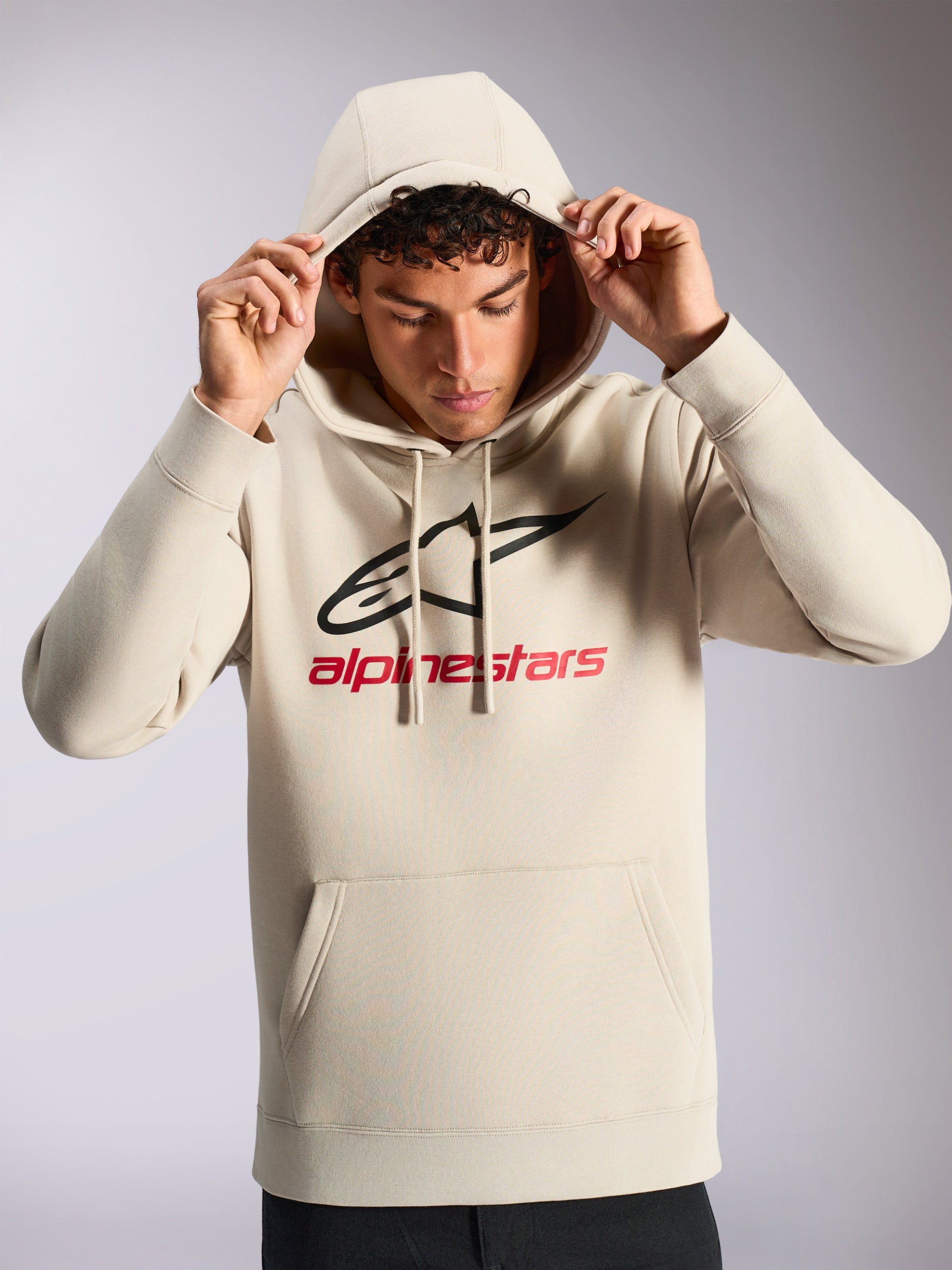 Alpinestars Always V3 Hoodie, male model wearing off-white pullover fleece, black and red front linear logo, drawstring hood, kangaroo pocket, casual motorsport-inspired streetwear