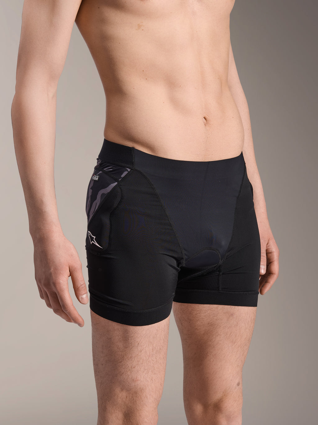 Alpinestars A-Motion Plasma Protection Boxers, black cycling base-layer shorts, featuring camo-patterned hip protector with white Astar logo, breathable mesh fabric, protective gear for mountain biking