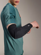 Alpinestars A-Motion Plasma Elbow Sleeve, Cycling Elbow Protector, Black, worn by a rider with a teal jersey, featuring the Alpinestars logo and Nucleon Plasma branding, sleek and breathable design for MTB protection