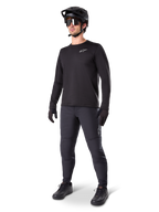 Mountain bike rider wearing Alpinestars A-Dura Thermal Pants, Black, styled with a black long-sleeve jersey, black helmet, and sunglasses, featuring a silver Alpinestars logo on the left thigh, designed for cold-weather trail riding