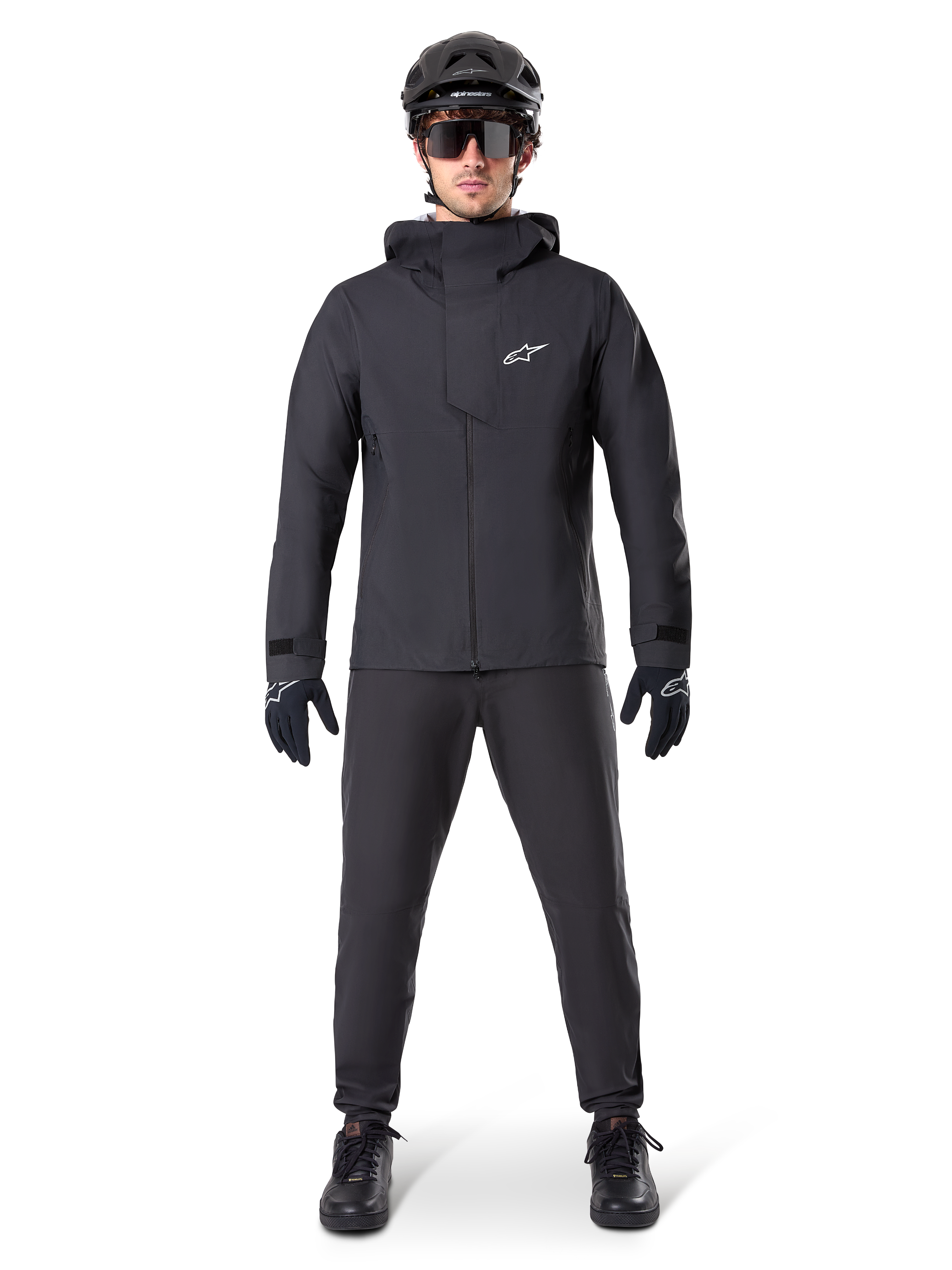 Alpinestars A-Dura Waterproof Pants, black MTB pants, worn as part of a complete all-black mountain biking gear set including a technical waterproof jacket, black helmet, sunglasses, and gloves, designed for wet-weather off-road riding.