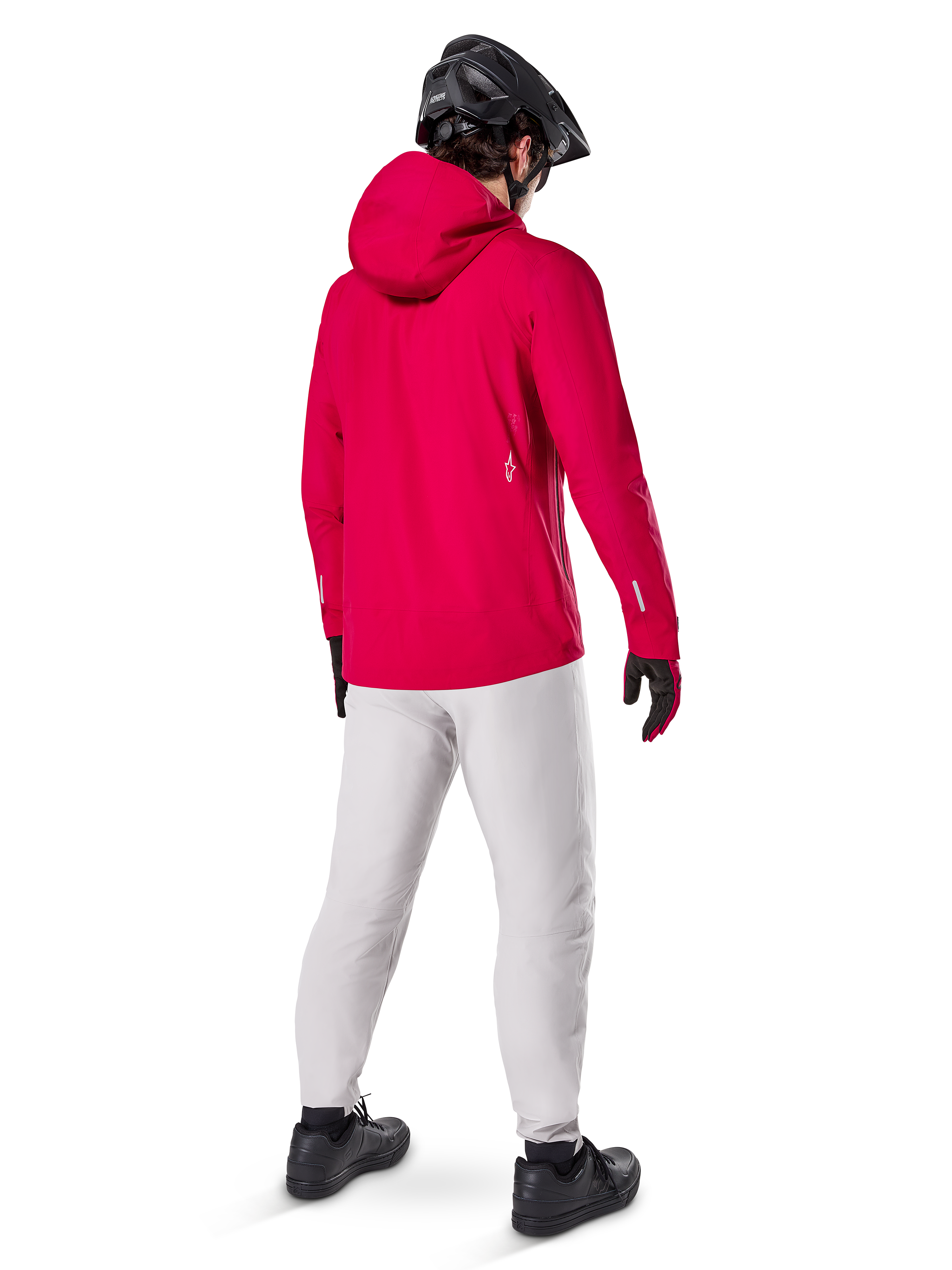 Alpinestars A-Dura Waterproof Pants in Titanium, rear view of a rider wearing the light gray technical mountain bike pants with a bright red hooded jacket and black helmet, durable waterproof gear for cycling in wet conditions