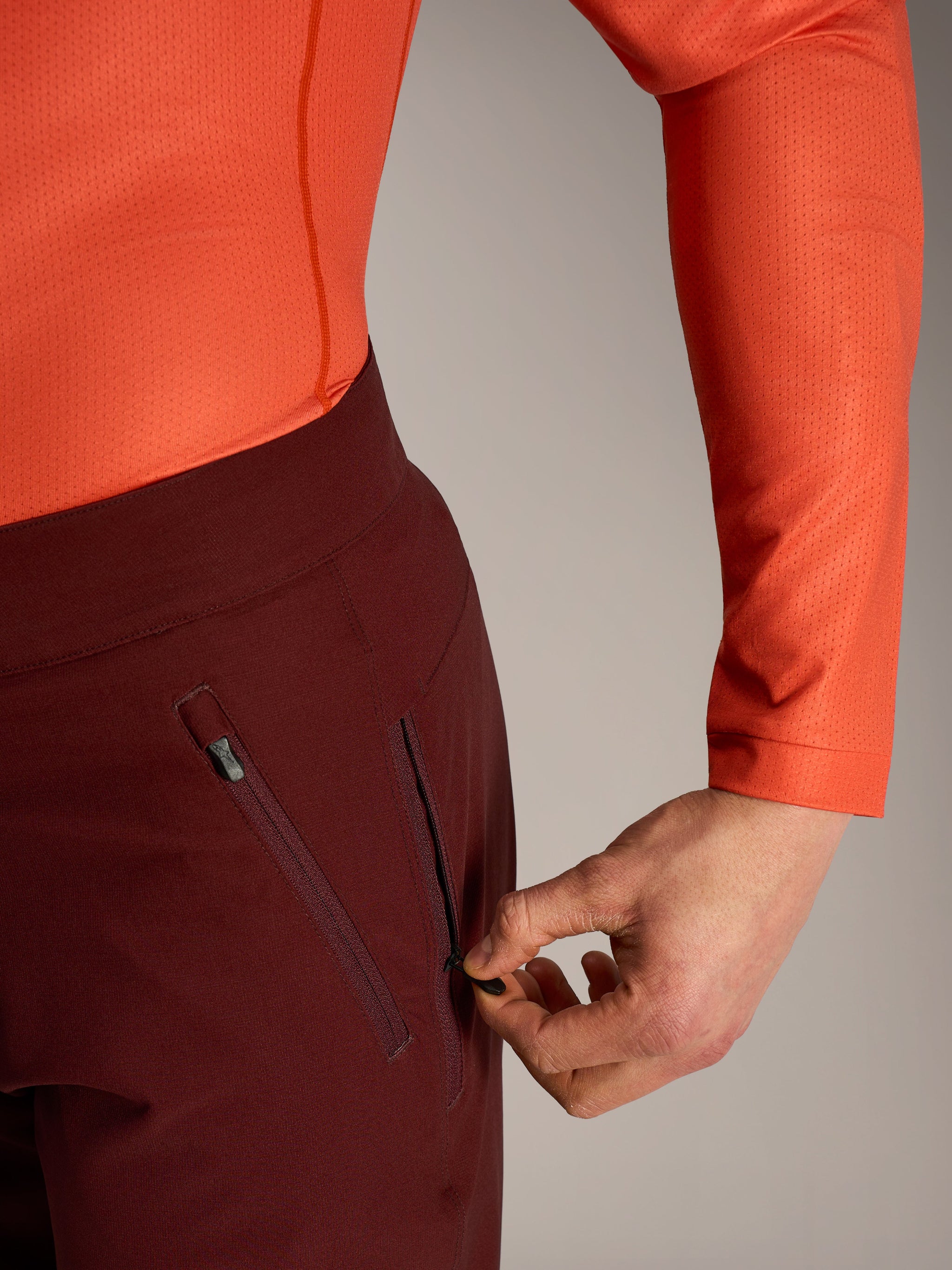 Alpinestars A-Dura Ride Shorts in bordeaux, detail of a hand opening the secure zippered mesh-lined side pocket.