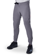 Alpinestars A-Aria Elite Pants, Dark Gray MTB Pants, laser perforated panels on thighs, black magnetic buckle closure, zippered pocket, red logo detail, slim performance fit, worn with black shoes