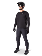 Model wearing Alpinestars A-Dura Thermal Jersey, Black long-sleeve MTB jersey, black mountain bike helmet, sunglasses, and dark grey pants, featuring a small white logo on the chest, insulated fleece construction for cold-weather riding