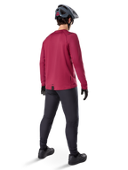 Alpinestars A-Dura Thermal Jersey, Burgundy long-sleeve cycling jersey, back view, worn with black mountain bike pants and a grey helmet, featuring an extended drop tail hem for rear coverage, mountain bike gear for cold weather