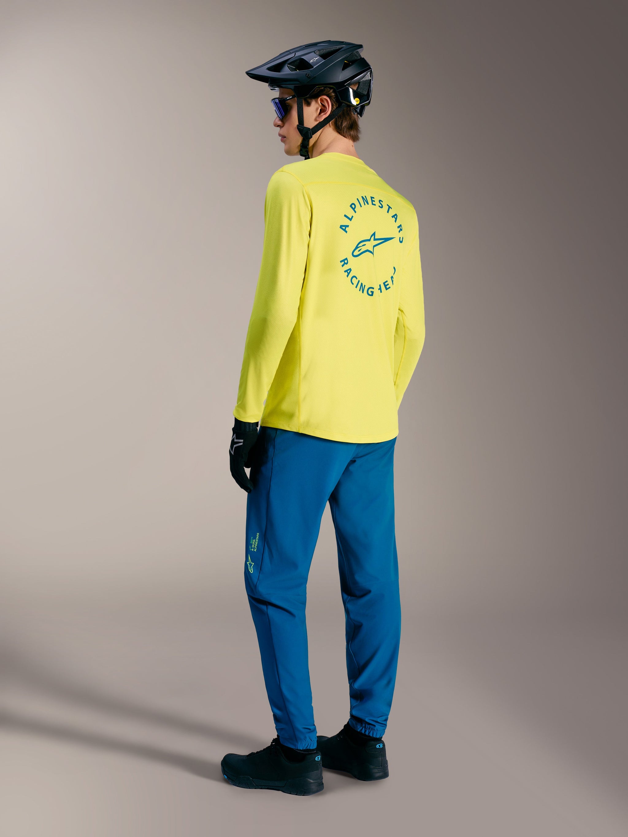 Yellow A-Dura Air Long Sleeve Jersey with blue circular back graphic, styled with blue MTB pants and a black helmet.