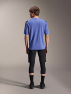 Male model from the back wearing Alpinestars mountain bike gear, light blue A-Aria Polartec Elite short sleeve jersey, black A-Aria Elite Shorts, black knee protectors, black socks, and black shoes, coordinated performance outfit for MTB.