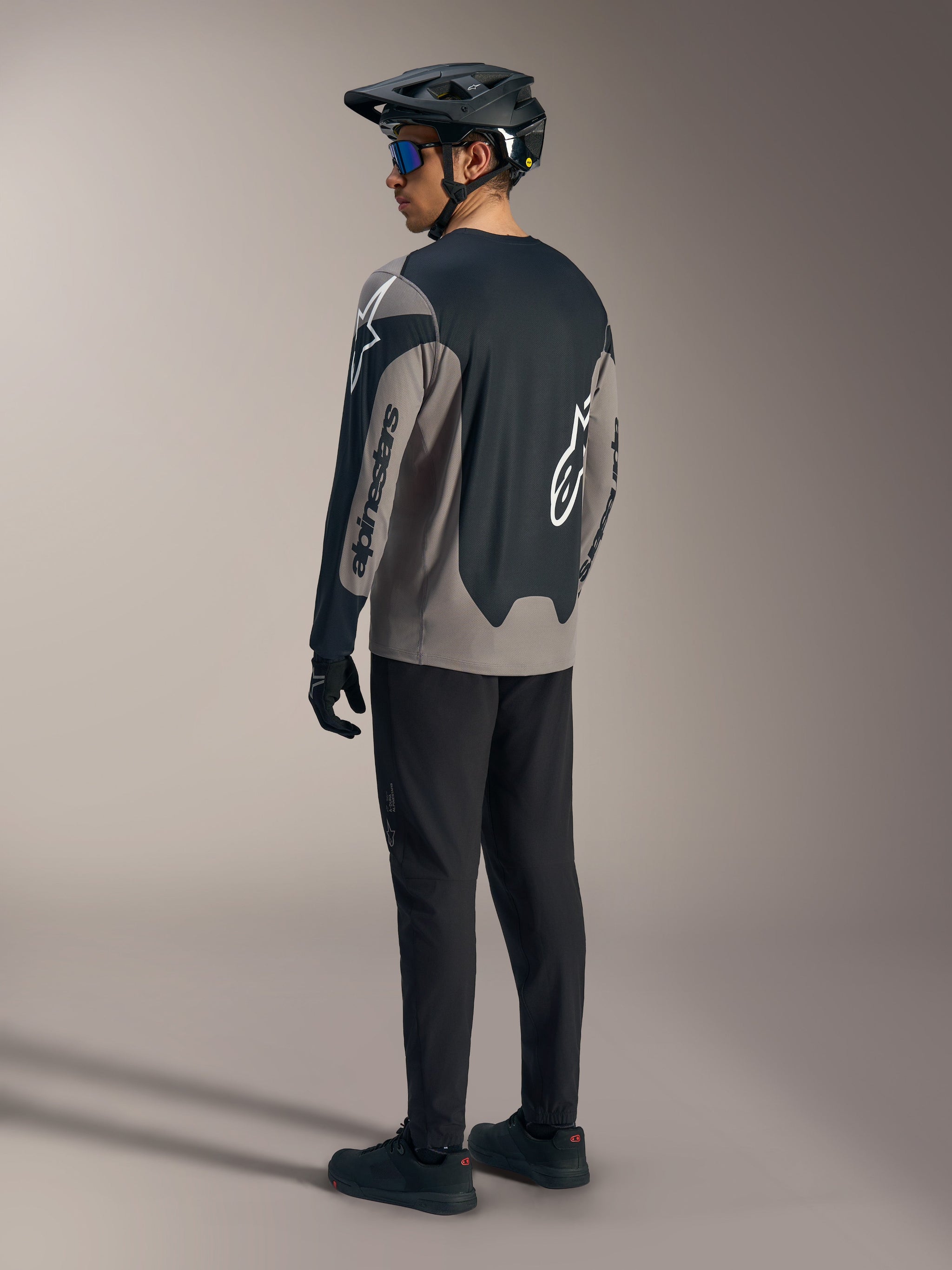 Gray and black A-Dura Race Long Sleeve Jersey, featuring Alpinestars branding, shown from behind in a full MTB kit.