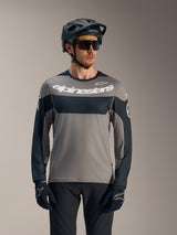 A-Dura Race Long Sleeve Jersey in gray and black with white Alpinestars logo, styled with MTB helmet for trail riding.
