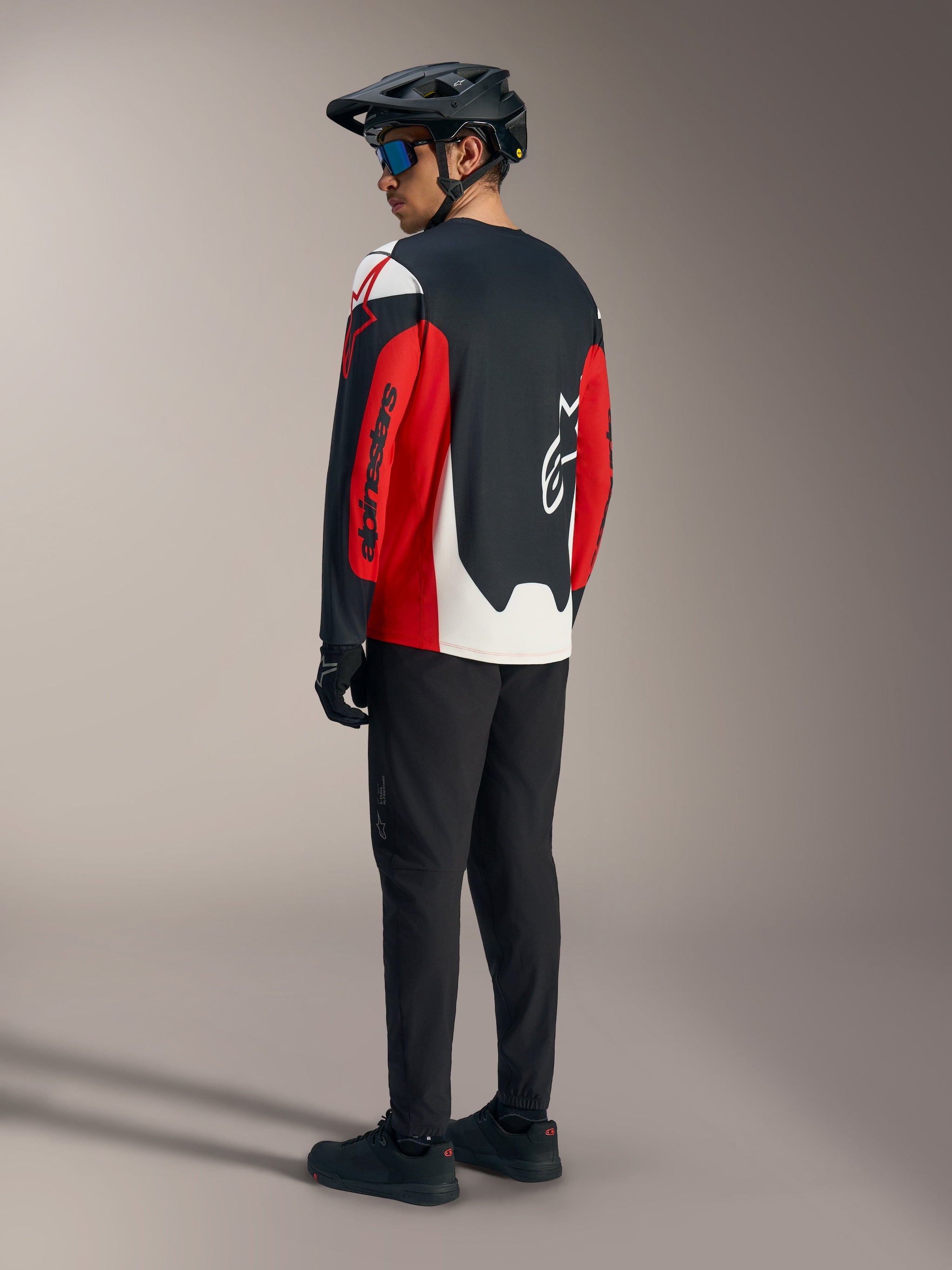Red A-Dura Race Long Sleeve Jersey featuring bold Alpinestars graphics, shown from the back in a mountain bike kit.