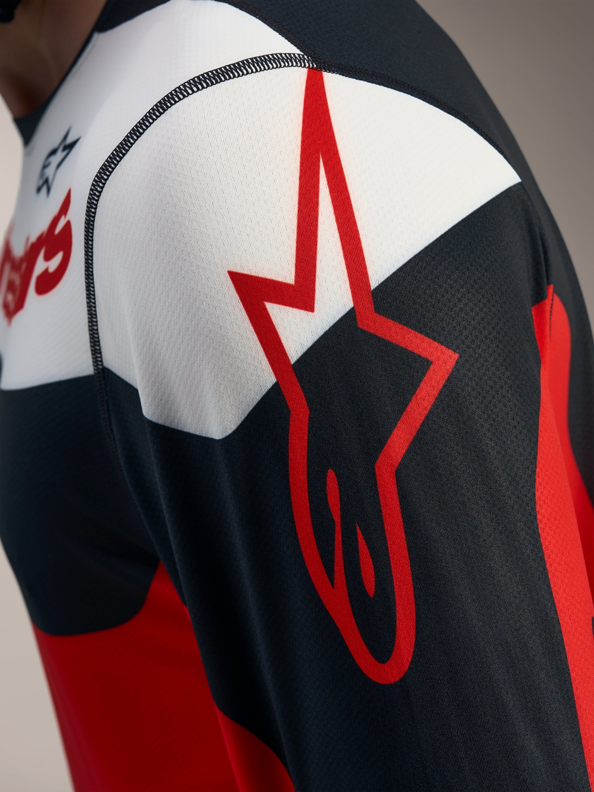 Red and black A-Dura Race Long Sleeve Jersey detail with an Alpinestars star logo on breathable jacquard mesh fabric.