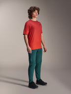 Model wearing Alpinestars A-Dura Pants in Dark Pine, paired with a red A-Dura Rise Short Sleeve Jersey and black MTB shoes, athletic mountain bike apparel in a studio setting