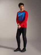 Red A-Dura Elite Long Sleeve Jersey 2.0 with blue striped chest panel and white logo, paired with black MTB pants.