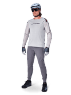 Alpinestars A-Aria Polartec Switch Jersey, Long Sleeve MTB Jersey, Light Gray, worn with dark gray mountain bike pants, helmet, and gloves, featuring laser-perforated sleeves and Alpinestars branding on the chest.