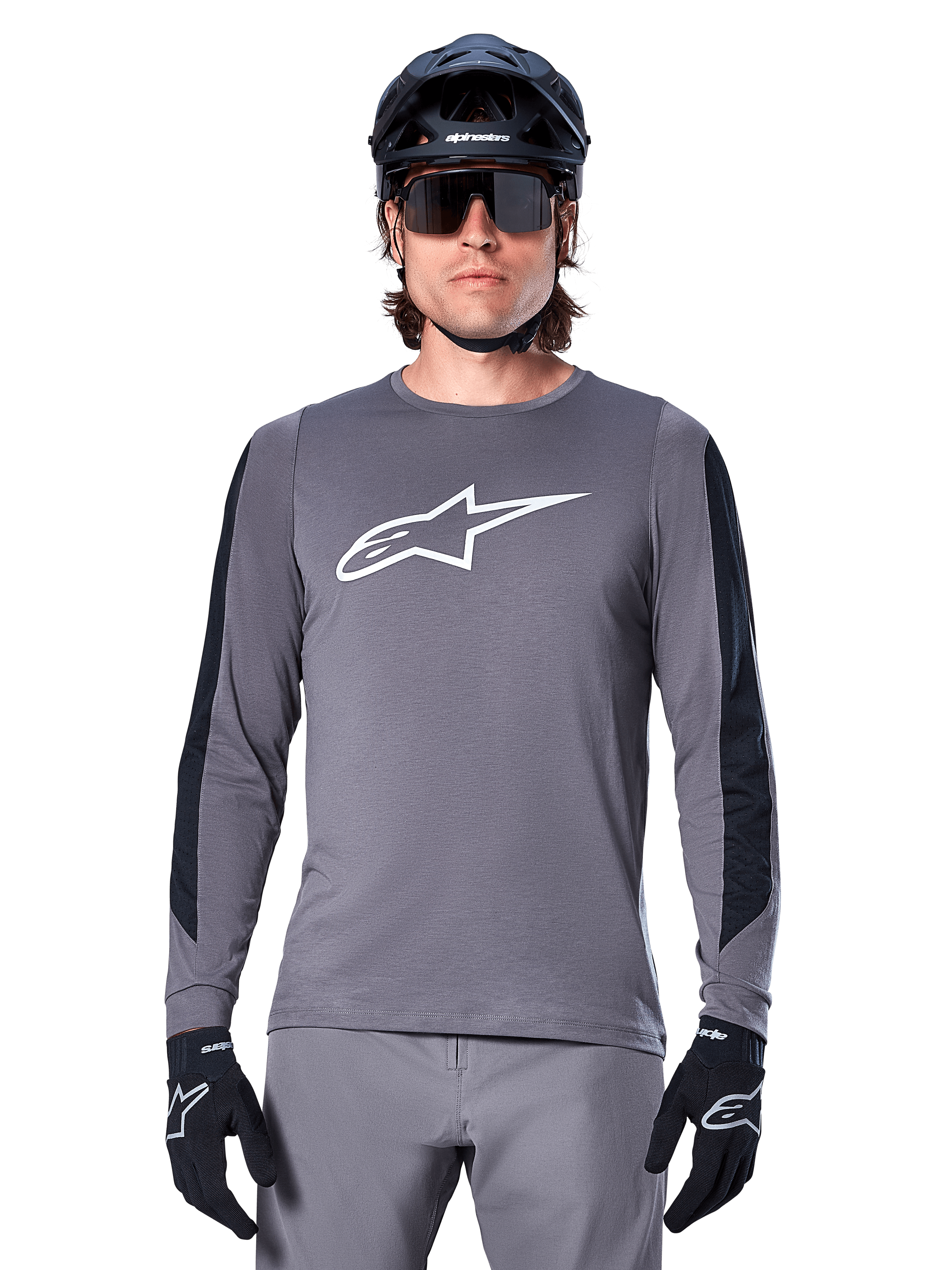 Alpinestars A-Dura Dri Astar Long Sleeve Jersey, Dark Gray, featuring a large white Astar logo on the chest and black mesh arm panels, worn by a rider with a black mountain bike helmet and performance sunglasses, MTB cycling apparel