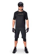 Alpinestars A-Aria Polartec Switch Jersey, Short Sleeve MTB Jersey, Black with tan lettering, worn with coordinated black mountain bike gear including helmet, shorts, and knee pads, performance off-road cycling apparel