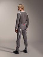Model from a rear view wearing Alpinestars MTB gear, gray A-Dura Dri Wool Long Sleeve Jersey, Dark Gray A-Dura Elite Pants with white vertical branding and red waistband detail, coordinated cycling outfit for mountain biking
