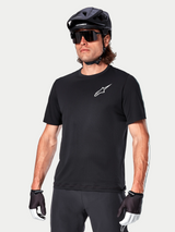 Alpinestars A-Aria Astar Short Sleeve Jersey in Black, worn by a cyclist with a black MTB helmet and sunglasses, featuring a white Astar logo on the chest, lightweight and breathable performance gear for trail riding