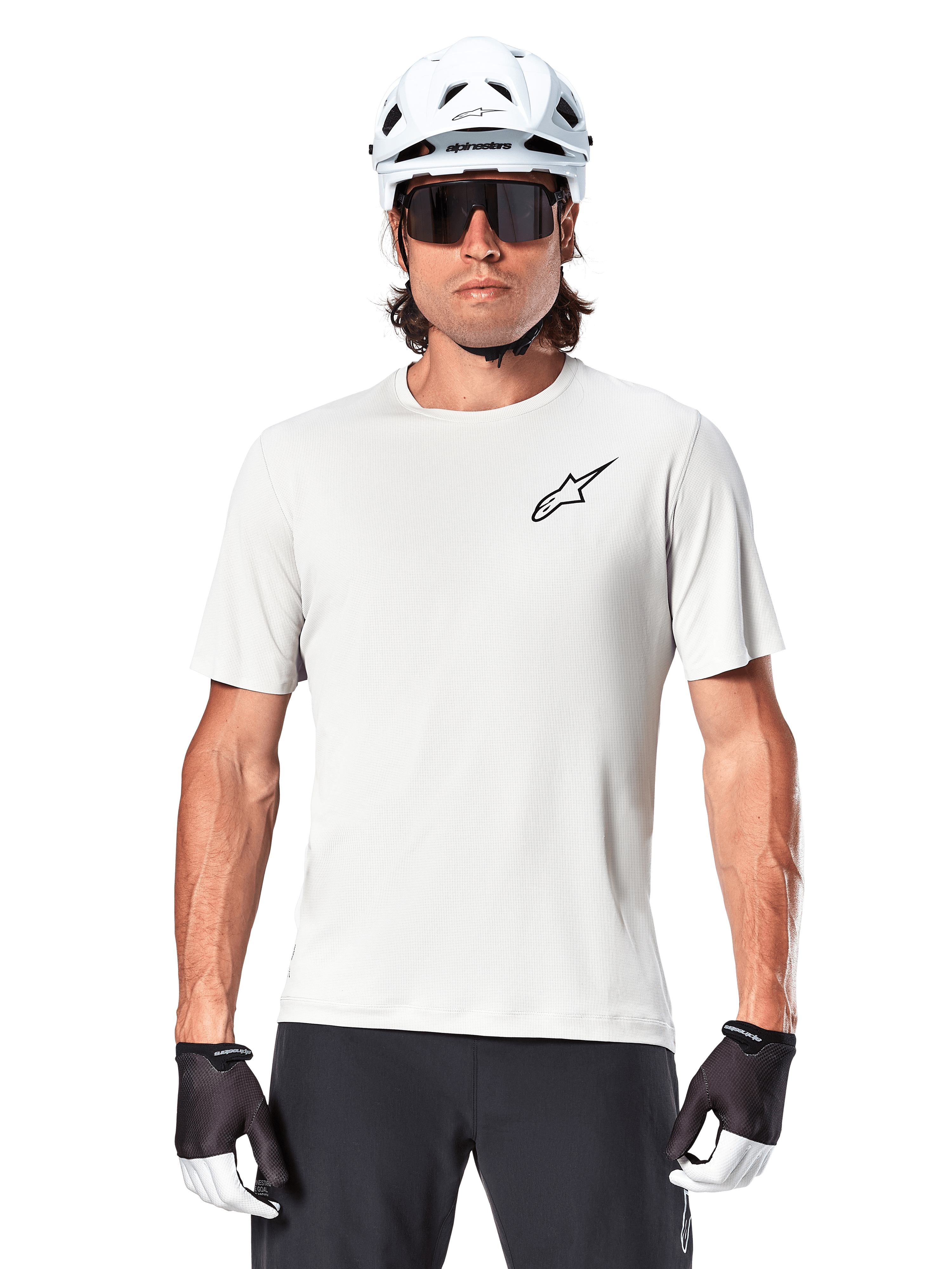 Cyclist wearing Alpinestars A-Aria Astar Short Sleeve Jersey, White Dove with small black Astar logo on chest, white cycling helmet, black sunglasses, and black and white gloves, performance MTB gear for off-road riding