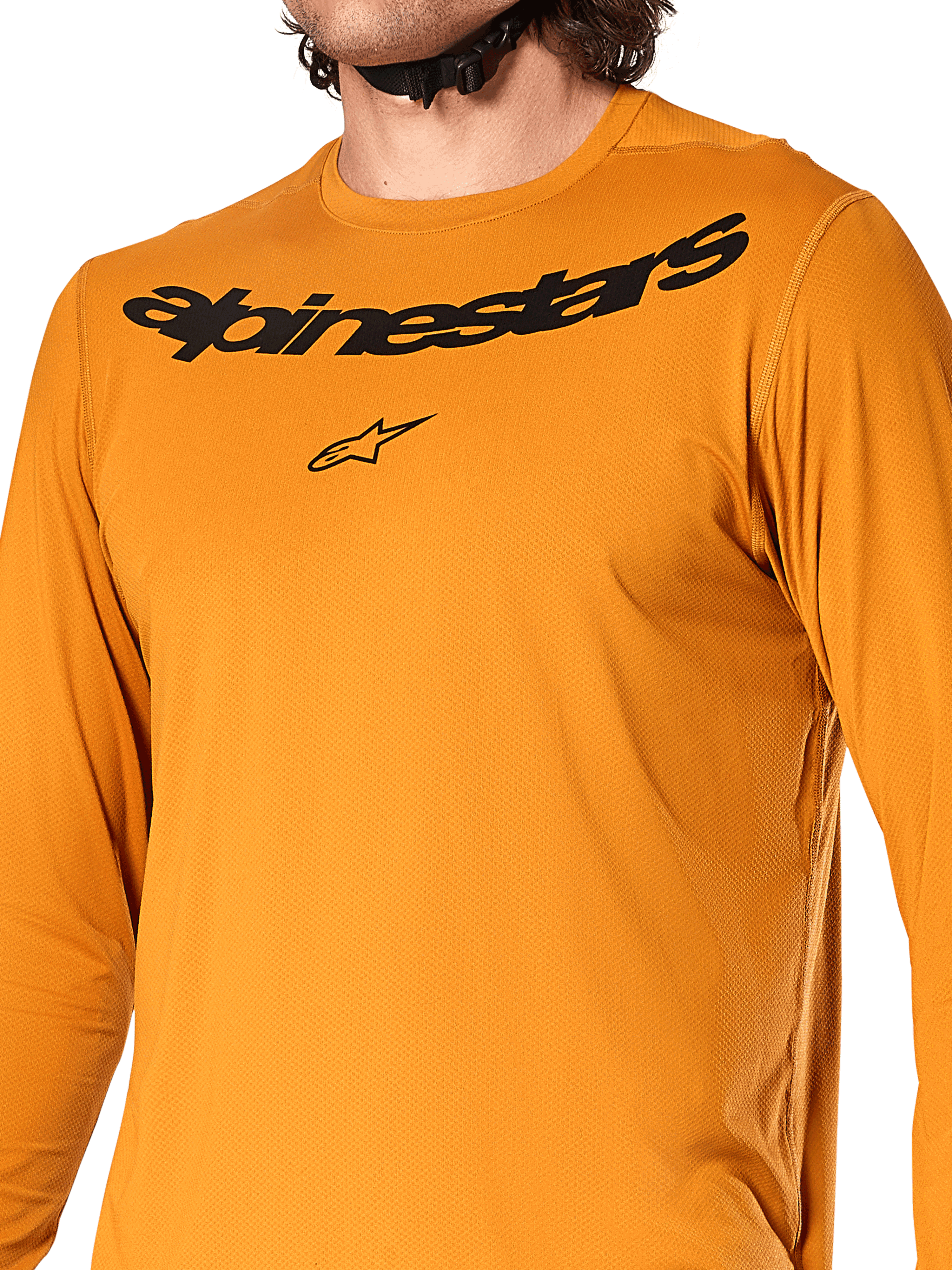 Alpinestars A-Dura Rocker Long Sleeve Jersey, Dark Gold, close-up view of chest featuring black Alpinestars wordmark and star logo, textured jacquard moisture-wicking fabric, performance MTB cycling apparel
