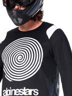 Alpinestars A-Supra Oscar Jersey, Long Sleeve, Black, featuring a large white Oscar spiral graphic on the chest and brand logo, worn by a rider with a black full-face helmet and goggles, performance mountain bike apparel for gravity riding